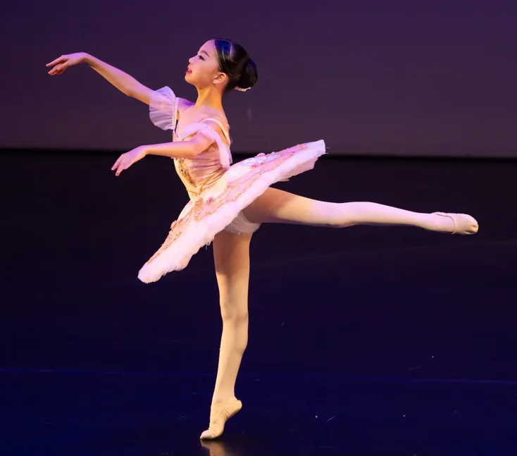 Young ballet dancer performing an arabesque en pointe on stage